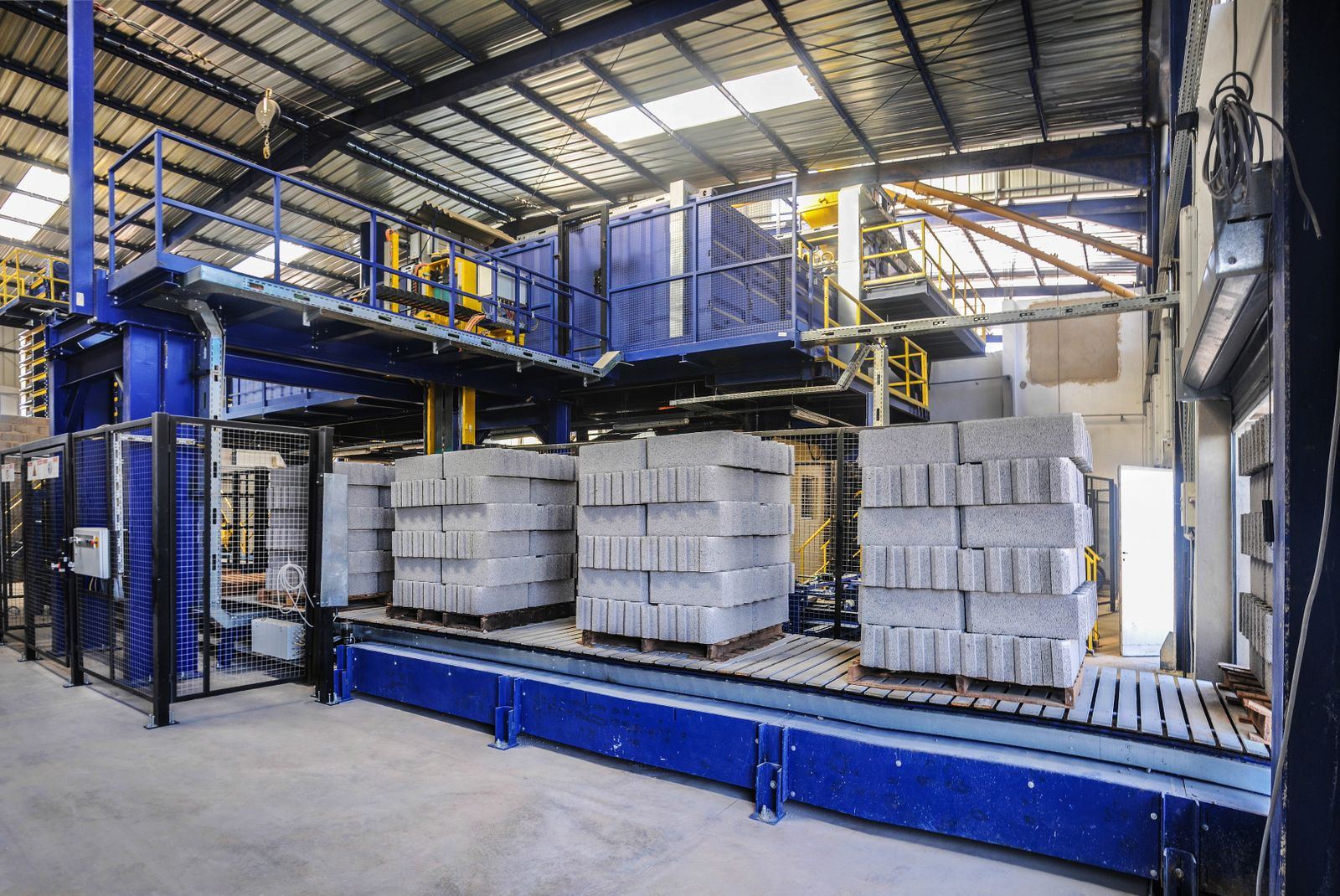Pallets of concrete blocks leaving a block plant on a roller conveyor — the kind of heavy, many-line stock a UAE building-materials distributor invoices every day.