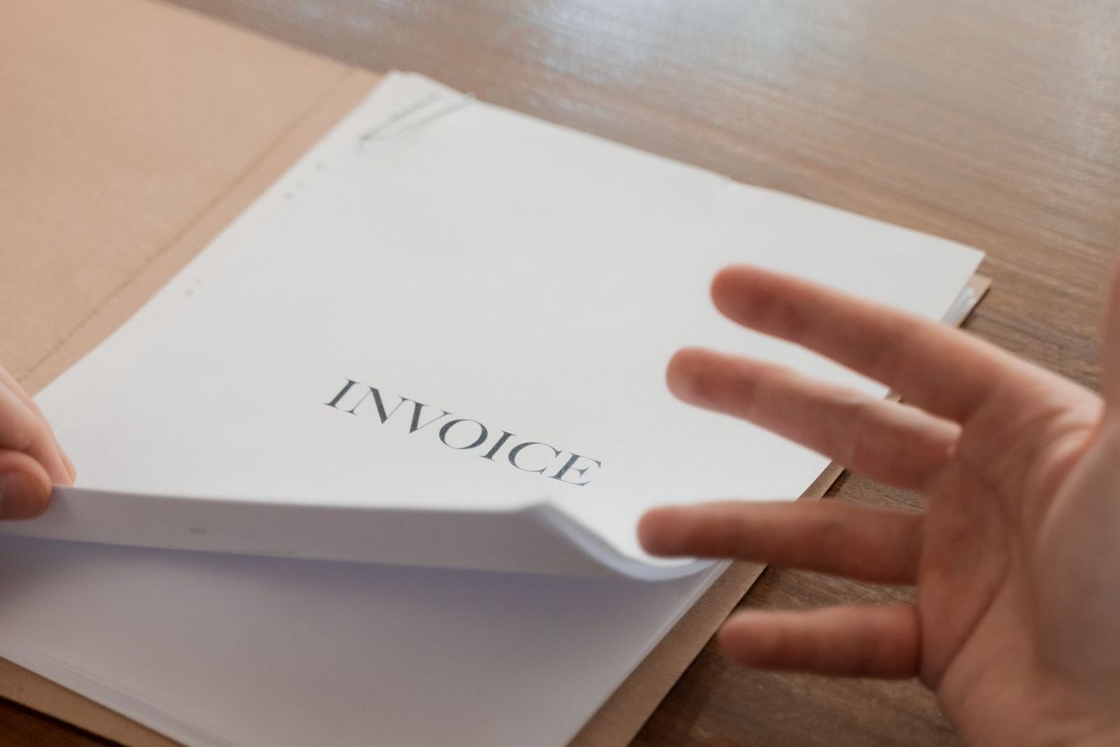 A printed invoice in a manila folder on an office desk — the paper and PDF tax invoice that UAE e-invoicing replaces for B2B sales.