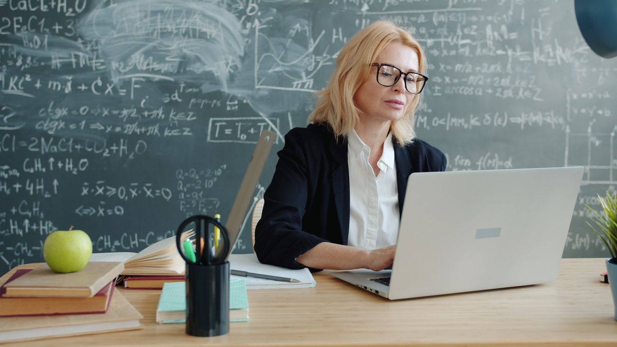 A teacher working on a laptop in a classroom